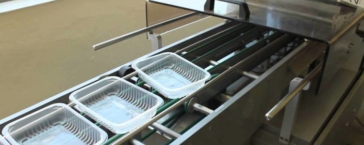 Процесс упаковки продуктов в лотки